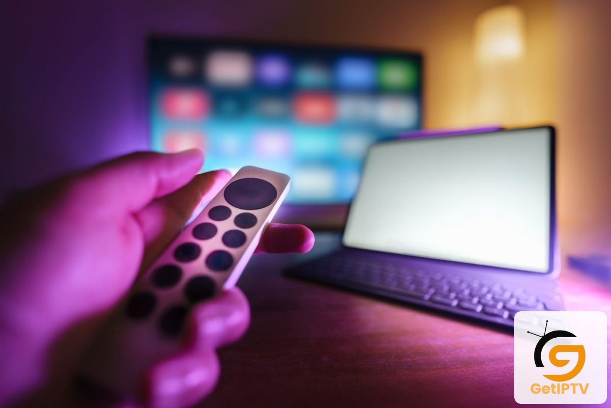 Photo of a person using a remote to control a TV and laptop; GetIPTV logo added